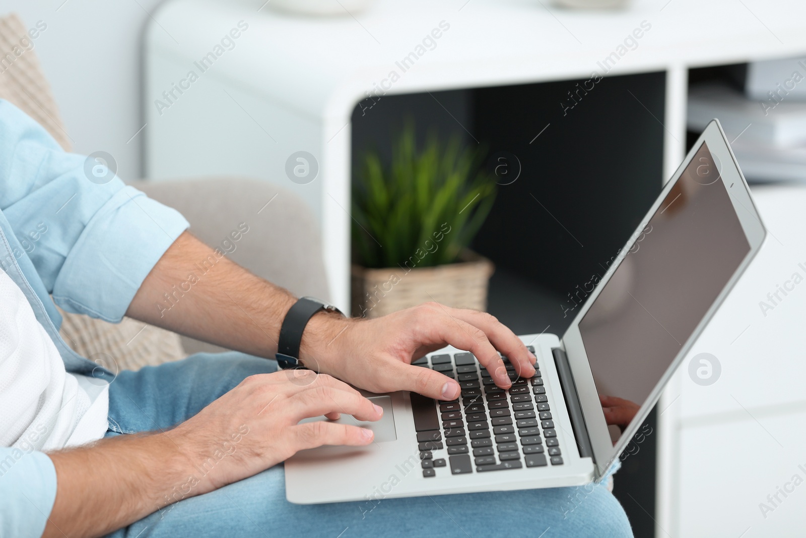 Photo of Young man working with laptop indoors, closeup