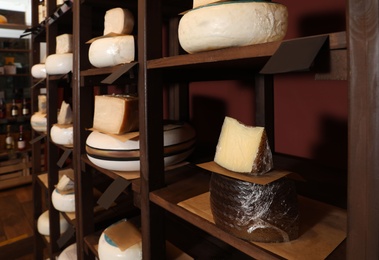 Different types of delicious cheeses on rack in store