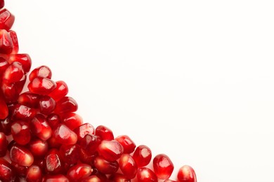 Photo of Many ripe juicy pomegranate grains on white background, flat lay. Space for text