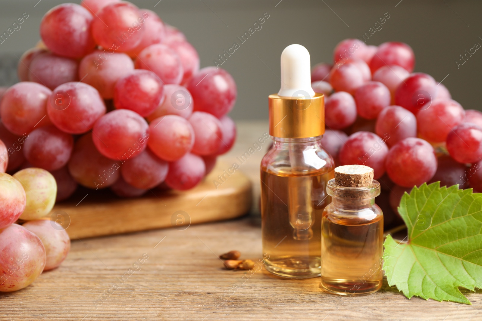 Photo of Natural grape seed oil and fresh berries on wooden table. Organic cosmetic