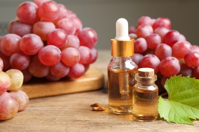 Photo of Natural grape seed oil and fresh berries on wooden table. Organic cosmetic