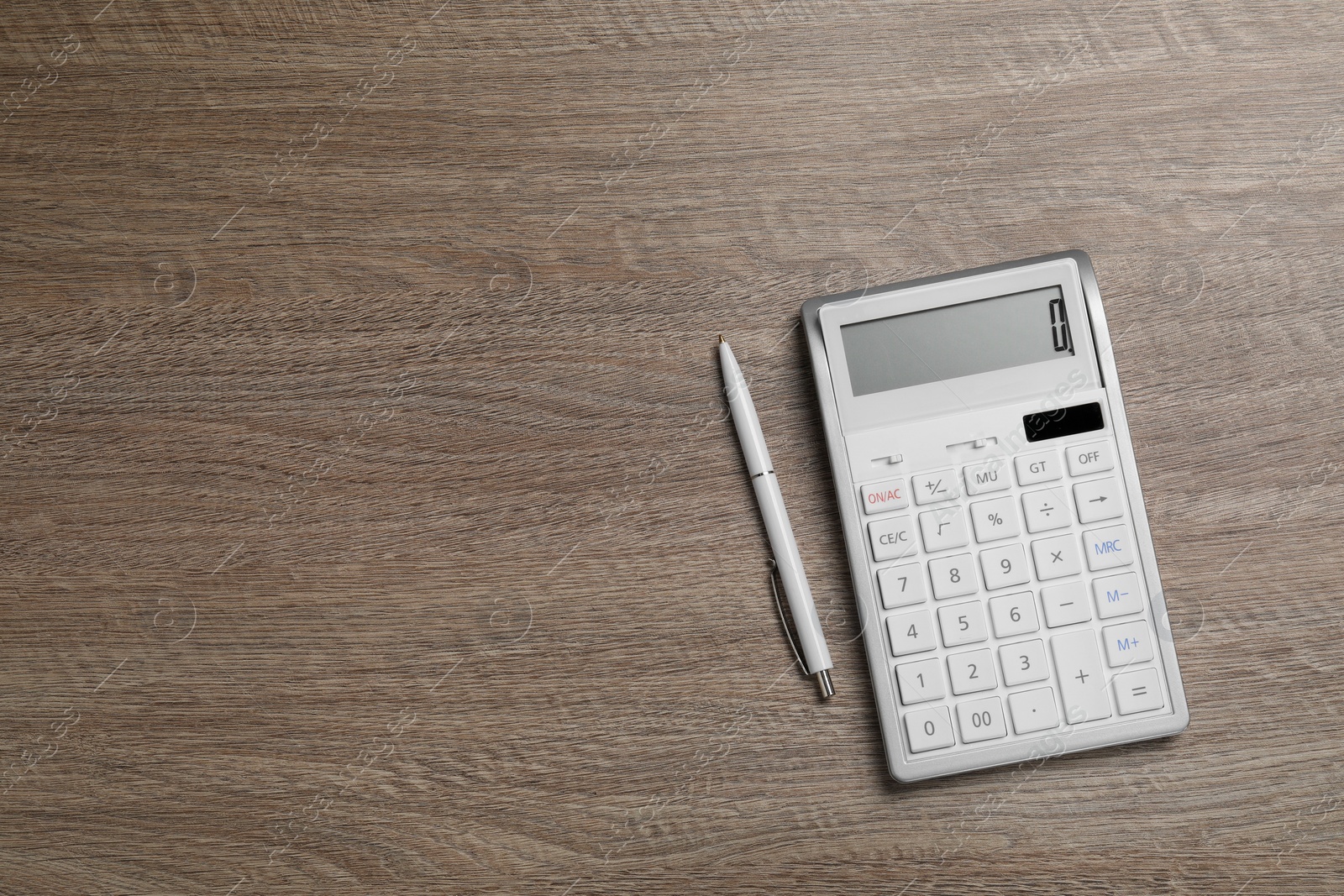 Photo of Calculator and pen on wooden table, top view. Space for text