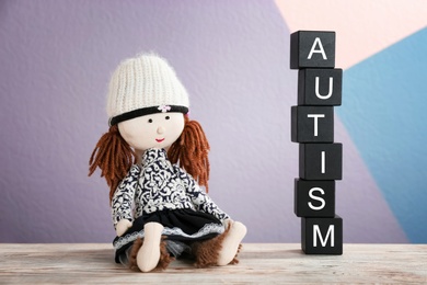 Photo of Doll and cubes with word "Autism" on table