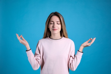 Photo of Young woman meditating on light blue background. Stress relief exercise