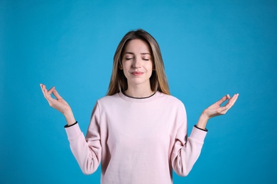 Young woman meditating on light blue background. Stress relief exercise