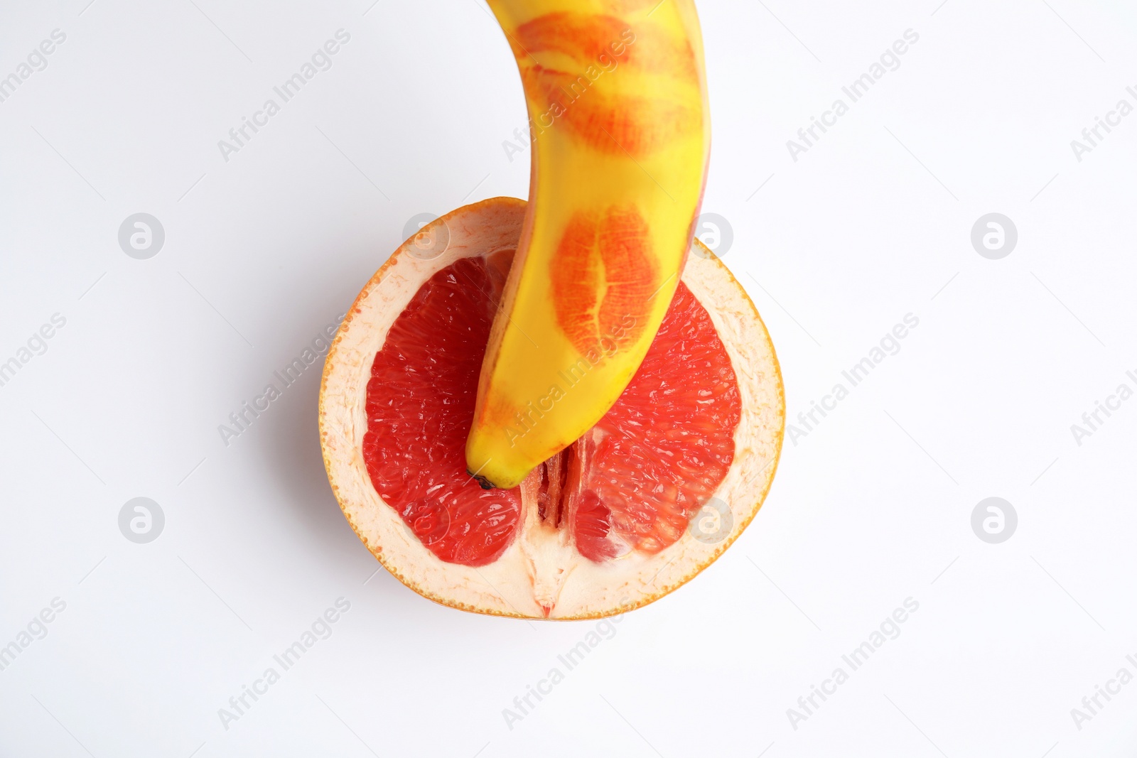 Photo of Fresh grapefruit and banana with red lipstick marks on white background, top view. Sex concept