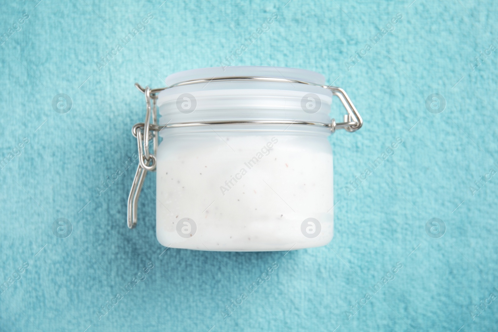 Photo of Jar of salt scrub on turquoise towel, top view