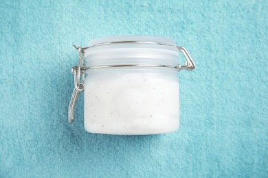 Photo of Jar of salt scrub on turquoise towel, top view