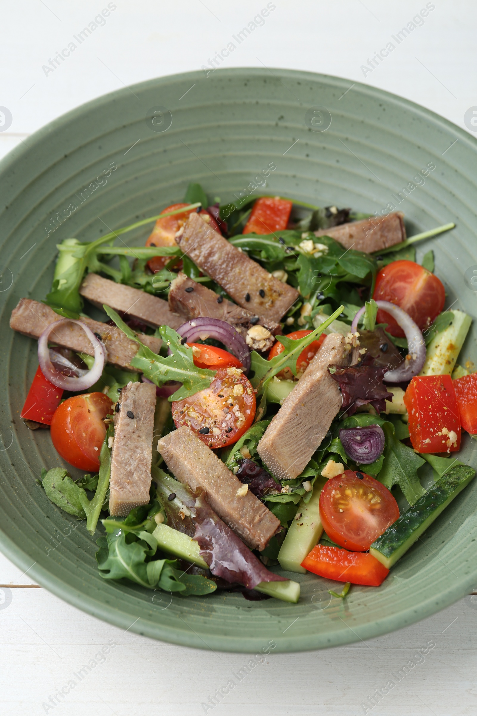 Photo of Delicious salad with beef tongue and vegetables on white wooden table, closeup