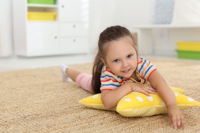Photo of Cute little girl with soft pillow toy on floor at home, space for text