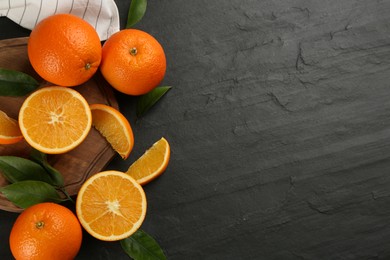 Photo of Delicious ripe oranges on black table, flat lay. Space for text