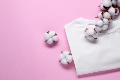 Cotton branch with fluffy flowers and white t-shirt on pink background, flat lay. Space for text