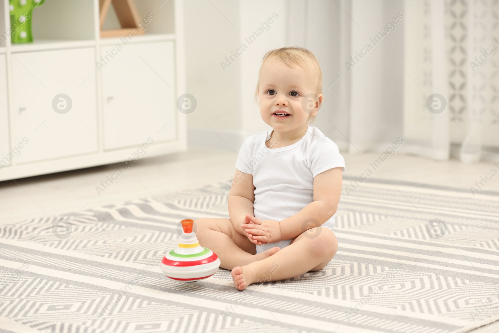 Photo of Children toys. Cute little boy and spinning top on rug at home