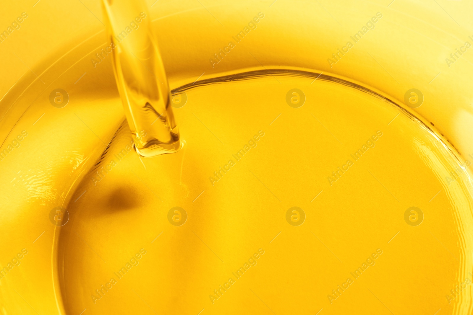 Photo of Pouring cooking oil into glass bowl, closeup