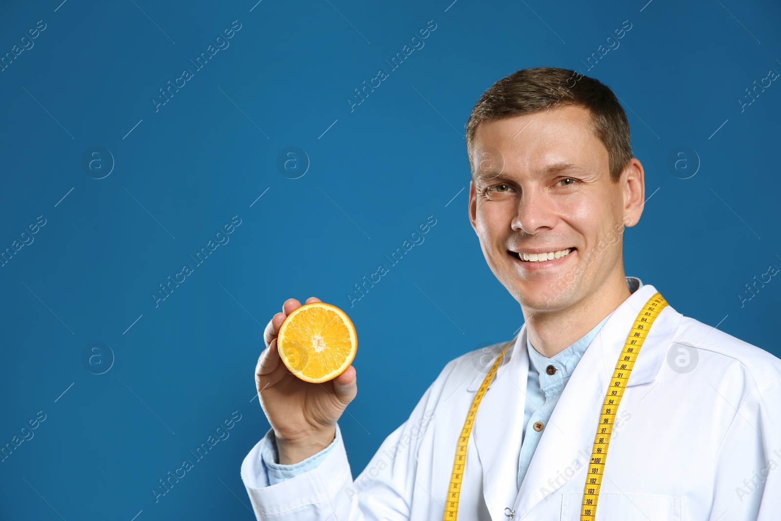 Photo of Nutritionist with orange on blue background. Space for text