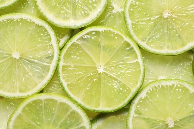 Juicy lime slices as background, top view. Citrus fruit