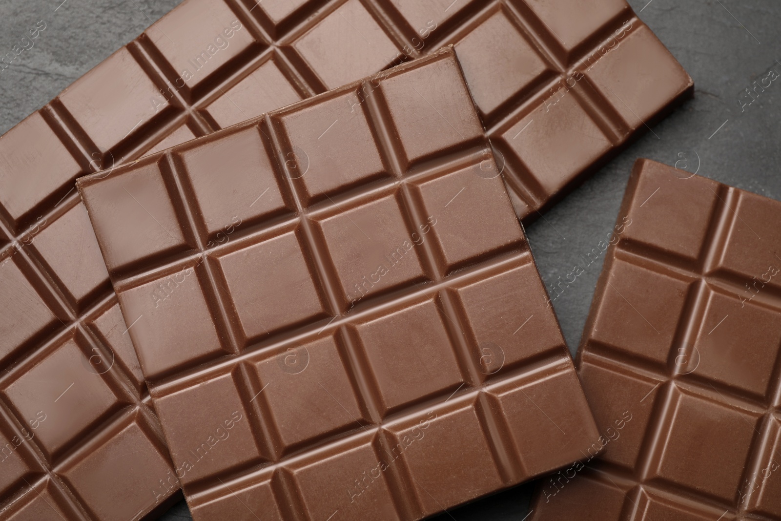 Photo of Delicious milk chocolate bars on black table, flat lay