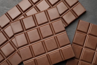 Photo of Delicious milk chocolate bars on black table, flat lay