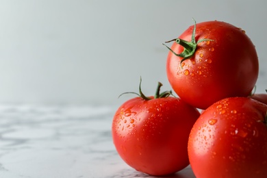 Photo of Fresh ripe tomatoes on white marble table, closeup. Space for text