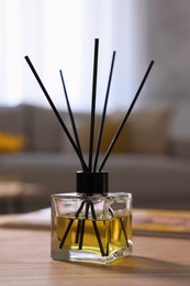 Photo of Reed diffuser on wooden table indoors. Cozy atmosphere