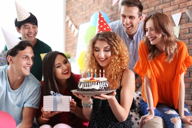 Photo of Young people celebrating birthday with tasty cake indoors