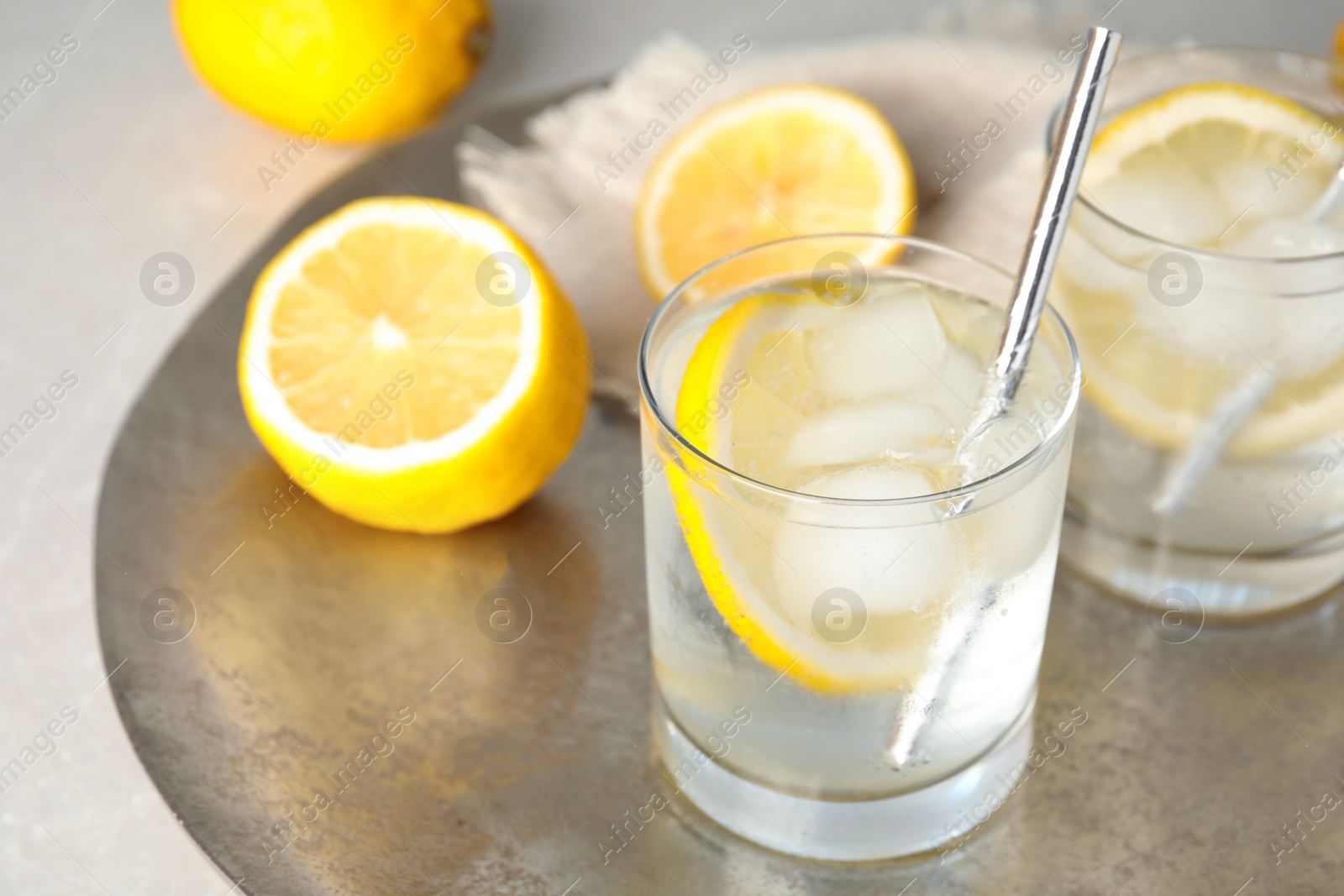 Photo of Soda water with lemon slices and ice cubes on silver tray