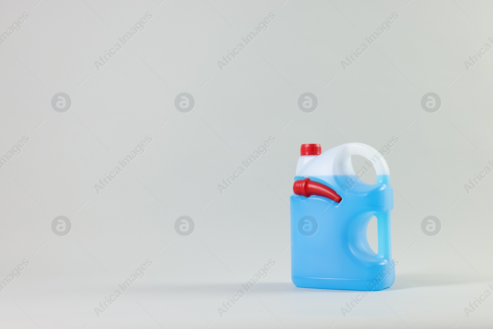 Photo of Plastic canister with nozzle and blue liquid on light grey background, space for text