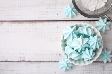 Photo of Tasty meringue cookies in bowl on white wooden table, top view. Space for text