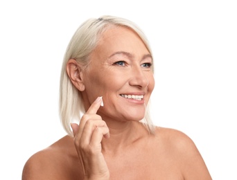 Photo of Mature woman applying face cream on white background