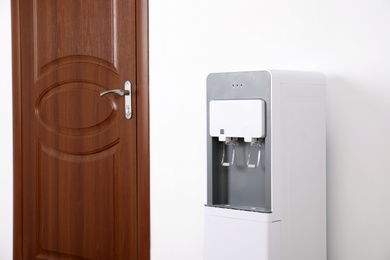 Photo of Modern water cooler near entrance indoors