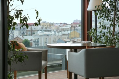 Observation area cafe. Table, armchairs and green plants on terrace against beautiful cityscape