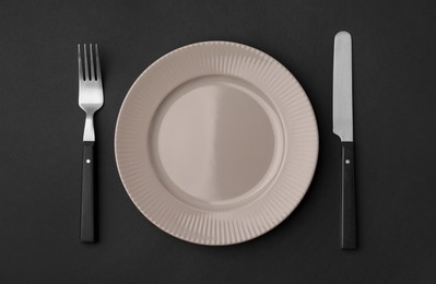 Photo of Clean plate with cutlery on black background, flat lay