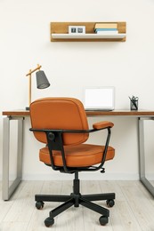 Stylish office interior with comfortable chair, desk and laptop