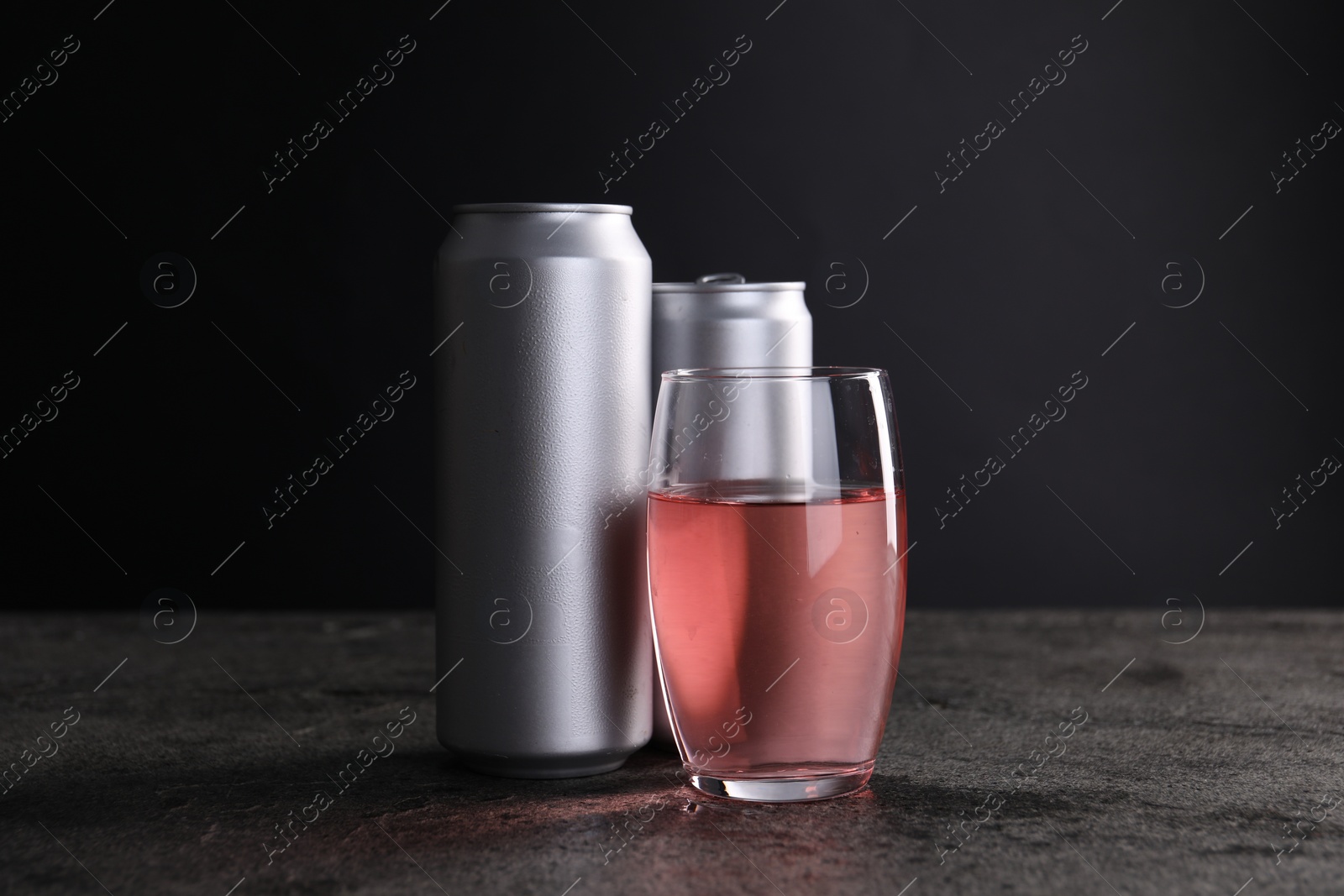 Photo of Energy drink in glass and aluminium cans on grey table