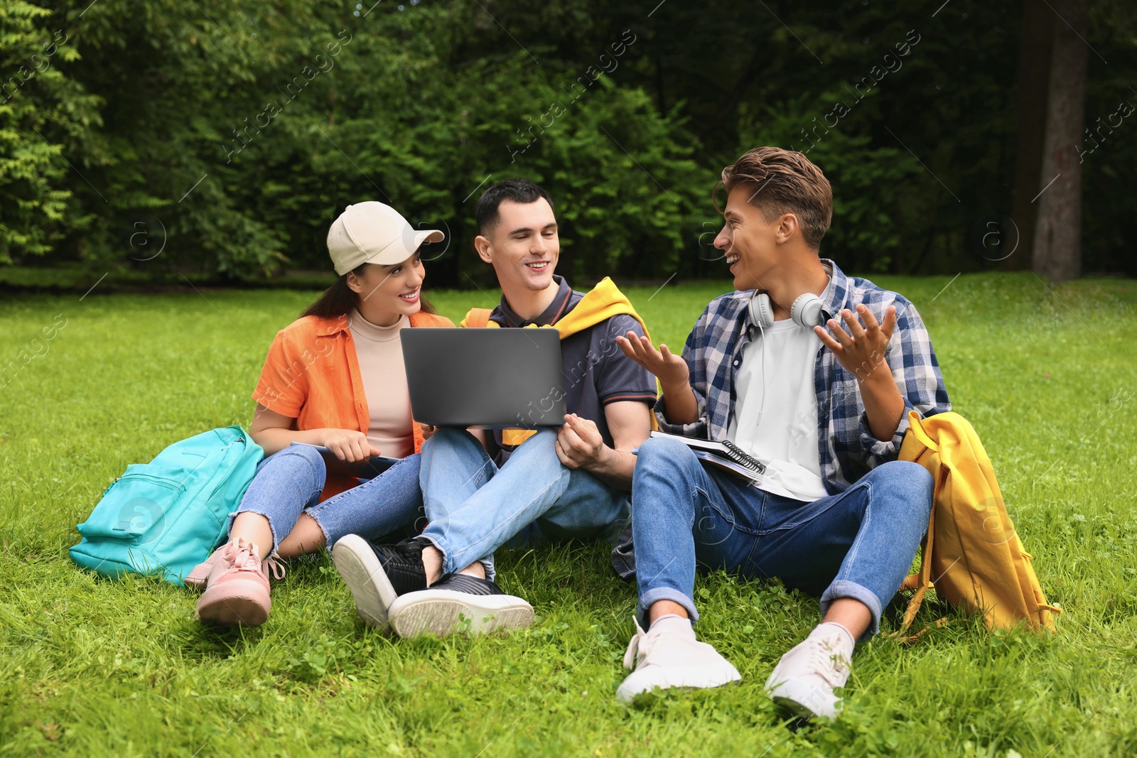 Photo of Happy young students learning together on green grass in park