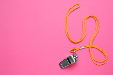 Photo of One metal whistle with cord on pink background, top view. Space for text