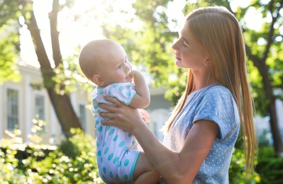 Teen nanny with cute baby outdoors on sunny day