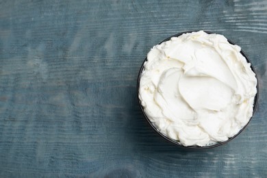 Tasty cream cheese on light blue wooden table, top view. Space for text