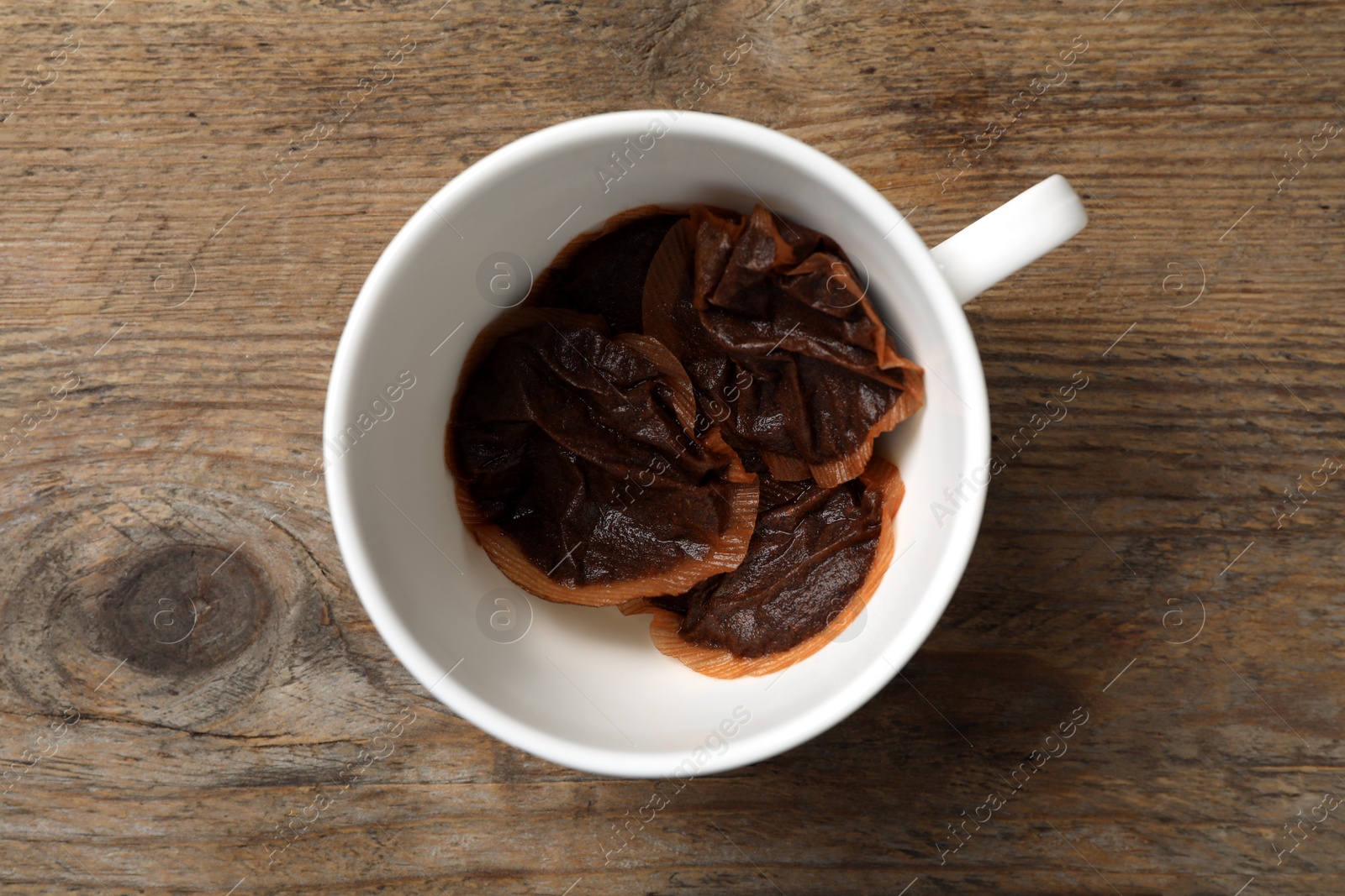 Photo of Cup with used tea bags on wooden table, top view