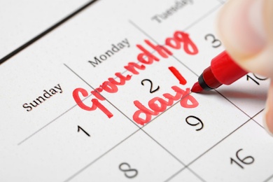 Woman marking date of Groundhog day in calendar, closeup