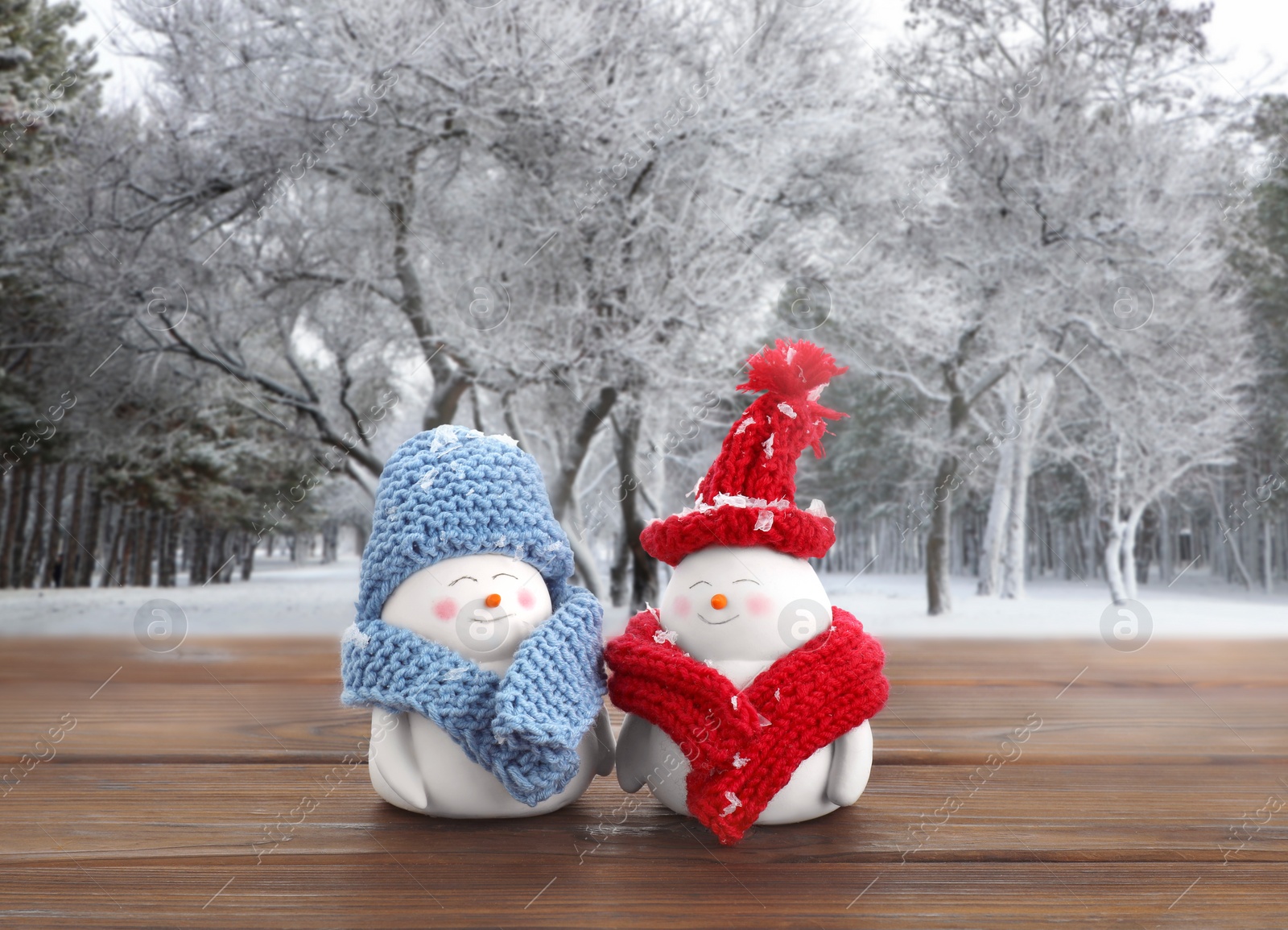 Image of Cute decorative snowmen on wooden table in snowy forest