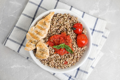 Photo of Tasty buckwheat porridge with meat on grey marble table, top view