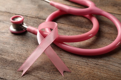 Photo of Pink ribbon and stethoscope on wooden background. Breast cancer concept
