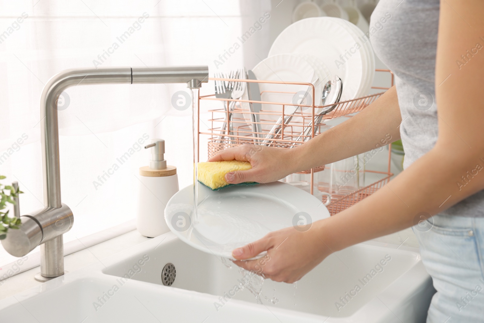 Photo of Woman washing plate at sink in kitchen, closeup