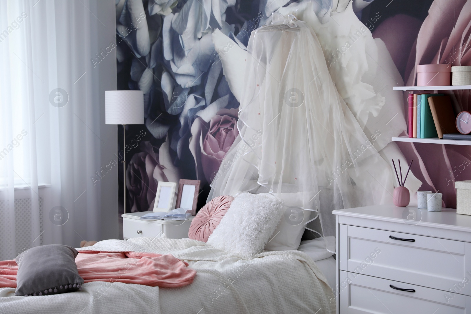 Photo of Teenage girl's room interior with comfortable bed and floral wallpaper. Idea for stylish design