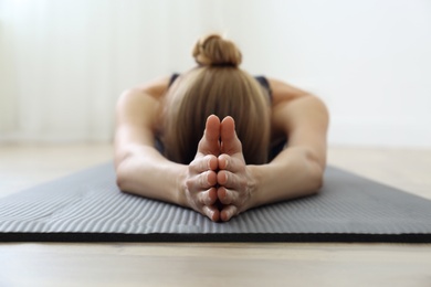 Photo of Young woman practicing restorative asana pose in yoga studio, focus on hands