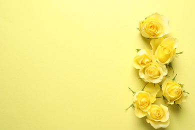 Photo of Beautiful roses on yellow background, flat lay. Space for text