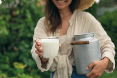 Photo of Smiling woman holding can and glass with fresh milk, closeup
