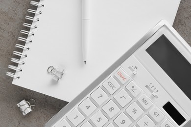 Ballpoint pen, notebook and calculator on gray table, flat lay