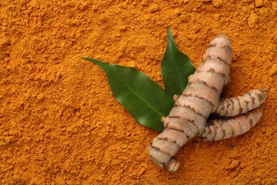 Raw root and leaves on aromatic turmeric powder, top view. Space for text